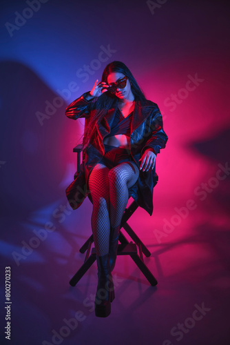 A woman is sitting in a chair with a black jacket and black stockings