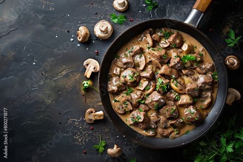Mushroom beef stroganoff in frying pan on dark rustic texture top view with space for text photo