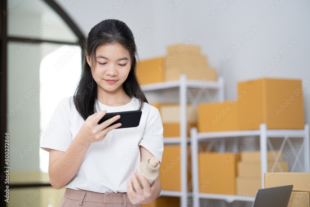 Young Asian business entrepreneur using a smartphone take a photo of product for upload to website online shop. Young Asian business entrepreneur using a smartphone take a photo of product for upload to website online shop.