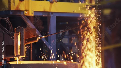 Bright yellow and orange sparks a splashing and flying from the furnace at modern steel manufacture plant. Metal cast in the foundry, hot liquid steel. Metallurgy. close up, slow motion