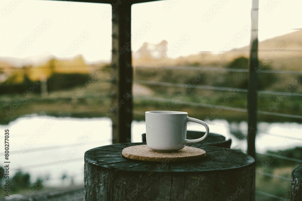 Naklejka premium Cup placed on a wooden log against a serene lake