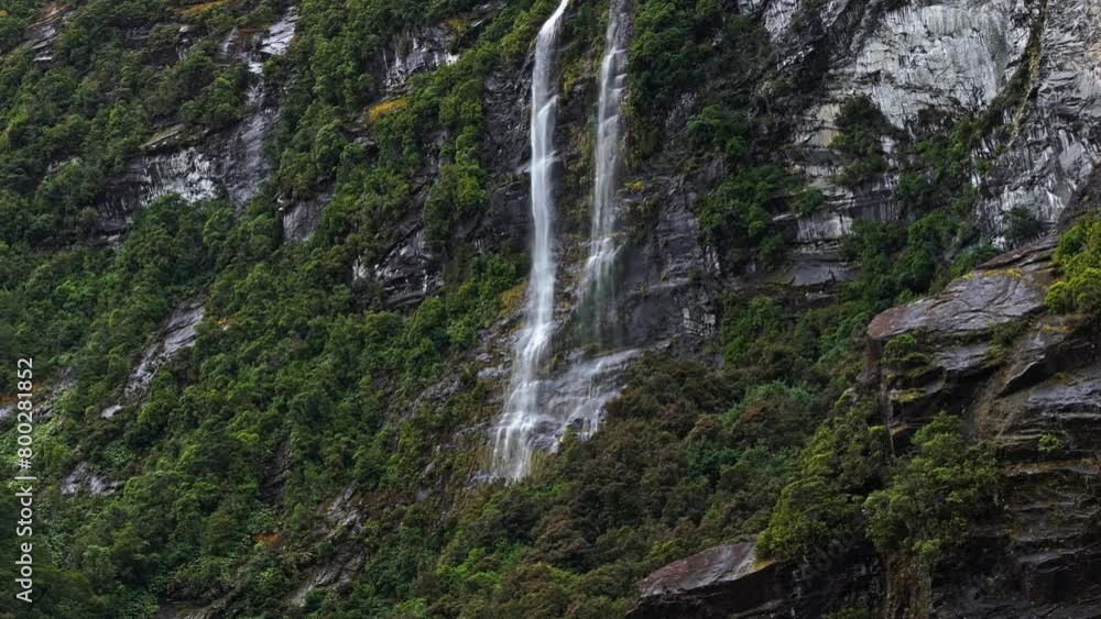 Aerial ascend pans across waterfall cascading along white rock and tropical vegetation Aerial ascend pans across waterfall cascading along white rock and tropical vegetation