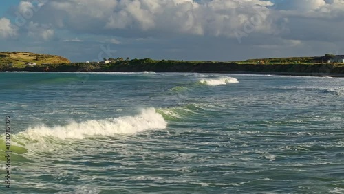 Aerial tracking pan follows ocean wave breaking into whitewash photo