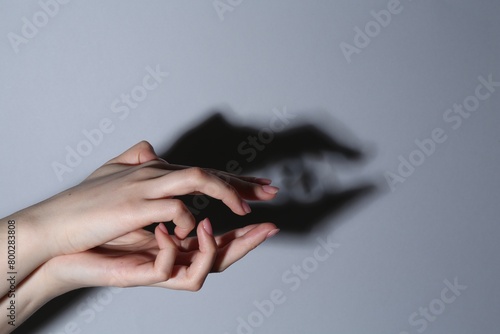 Shadow puppet. Woman making hand gesture like crocodile on grey background, closeup