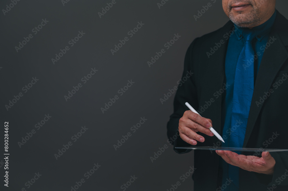 businessman in a suit is writing on a tablet with a white pen. Concept of professionalism and focus, as the man is dressed in a suit and tie and is using a tablet to take notes or complete a task businessman in a suit is writing on a tablet with a white pen. Concept of professionalism and focus, as the man is dressed in a suit and tie and is using a tablet to take notes or complete a task