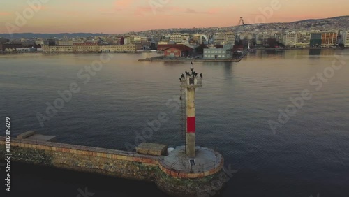 Lighthouse During Sunset at Thessaloniki Waterfront: Aerial Drone Showcases Lighthouse With Birds, Backdrop of the City Skyline - Captivating Views of Greek Urban Coastal Beauty Θεσσαλονίκη, Ελλάδα photo
