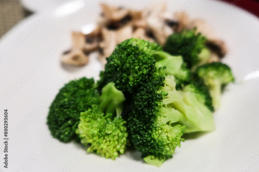 close up of raw broccoli vegetables with mushroom at the back on a white plate close up of raw broccoli vegetables with mushroom at the back on a white plate