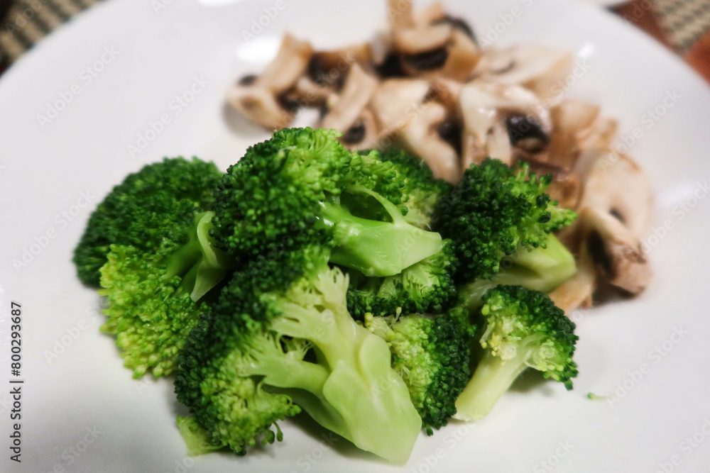 close up of raw broccoli vegetables with mushroom at the back on a white plate close up of raw broccoli vegetables with mushroom at the back on a white plate