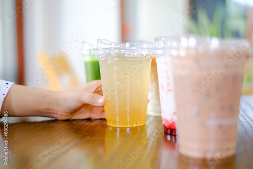 Woman hand hold plastic cup a lot of sweet or coffee on the wooden table background in cafe restaurant, celebrate,party, meeting