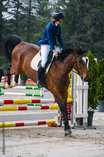 Beautiful young woman on her mare during a show jumping competition