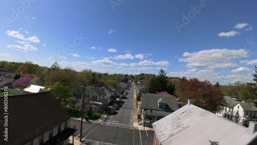 American town street during bright spring day. Aerial FPV drone shot over houses and homes.