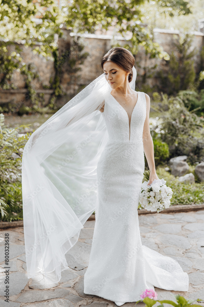 A bride in a white dress is walking with a veil in her hair. She is holding a bouquet of flowers A bride in a white dress is walking with a veil in her hair. She is holding a bouquet of flowers