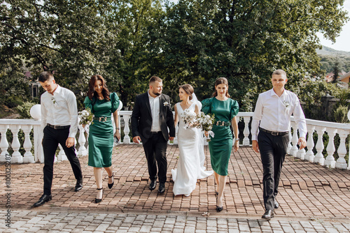 A group of people are walking down a brick walkway, with a bride and groom in the center