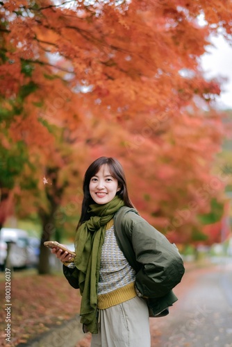 Asian woman in a stylish sweater  enjoying the fall season. A pretty and cheerful portrait capturing the essence of nature.