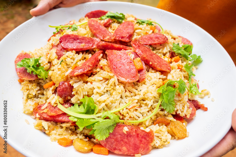 Com chien lap xuong or fried rice with sausage. A Vietnamese cuisine. Slices of Mai Que Lo or pork sausages are mixed with green peas, carrot cubes, dried shrimps. Fry them with eggs, rice, salt Com chien lap xuong or fried rice with sausage. A Vietnamese cuisine. Slices of Mai Que Lo or pork sausages are mixed with green peas, carrot cubes, dried shrimps. Fry them with eggs, rice, salt