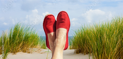 Damenbeine mit Roten Stoffschuhen am Strand