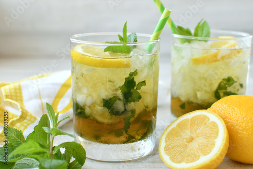 Cocktail or lemonade drink with lemon, muddled mint garnish, green straws, lemon slices photo