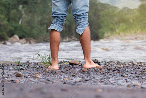 lifestyle. close-up of bare feet of a man on the bank of a rocky river © Andrey