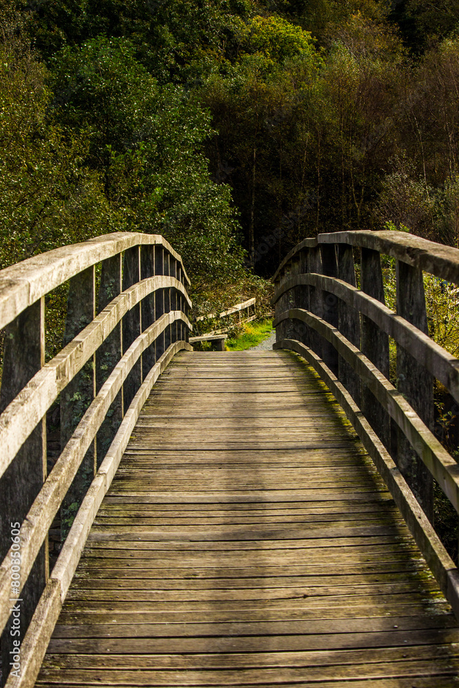A small wooden hiking bridge, crossing the River Glalyn, Aflon Glyslyn, in the Eryri National Park in Wales, on a sunny day A small wooden hiking bridge, crossing the River Glalyn, Aflon Glyslyn, in the Eryri National Park in Wales, on a sunny day
