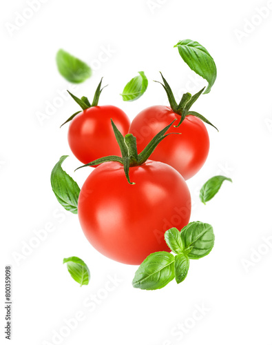 Flying tomatoes and basil leaves isolated on white background. Red tomatoes levitate on white background. Mockup for advertising or product packaging design. Perfect retouched.