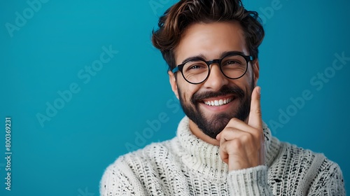 A Young handsome man with beard wearing casual sweater and glasses over blue background smiling doing phone gesture with hand and fingers like talking on the telephone, Communicating concepts photo
