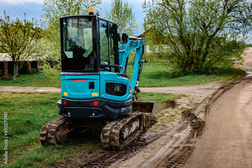 Mini excavator at the construction site for earthworks on road.