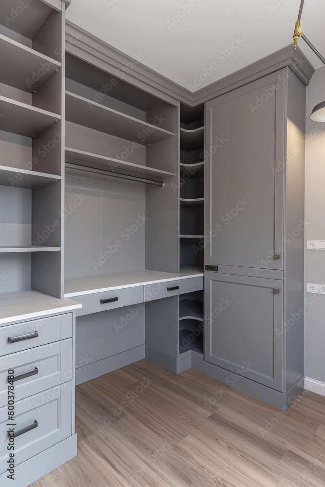 Fototapeta premium A grey and white wardrobe with shelves, light gray walls, neutral colors, modern design, light wood floor
