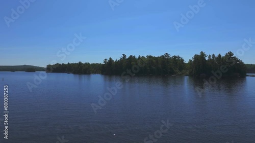 Drone capturing trees on islands while flying over scenic Ambajejus Lake against clear blue sky in Maine photo