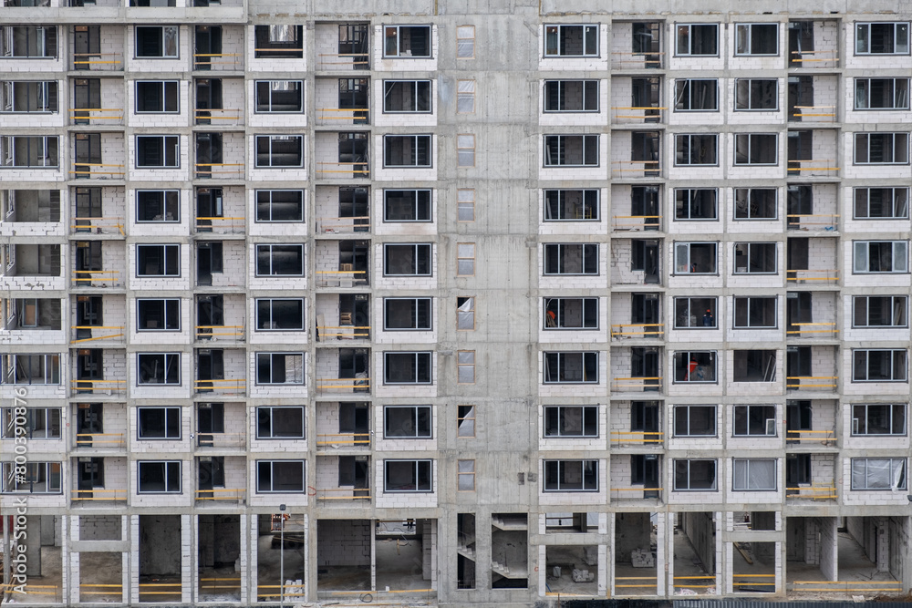 An unfinished cement building stands at a construction site during the summer