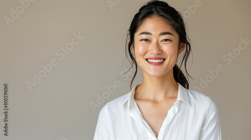 Portrait of a 30-year-old Japanese woman smiling slightly on a grey background. Asian woman with a gentle smile and loose hair