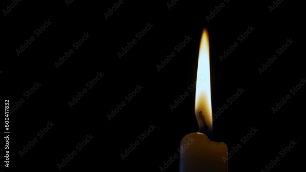 A single candle, made of wax, is gently illuminating the darkness with its warm flame. The flickering fire adds a touch of ambiance to the interior design of the room A single candle, made of wax, is gently illuminating the darkness with its warm flame. The flickering fire adds a touch of ambiance to the interior design of the room