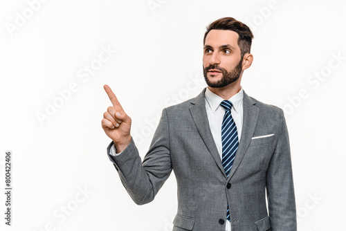 Confident young businessman in formal tuxedo pointing on copyspace isolated over white background. Successful boss banker lawyer promoting, showing with finger free blank space