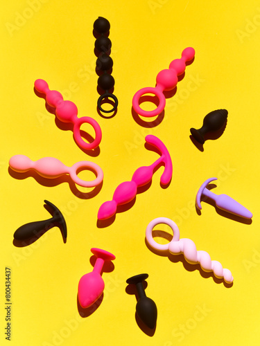 Bright sex toys background. anal plugs and dildo over yellow paper backdrop © Nik_Merkulov