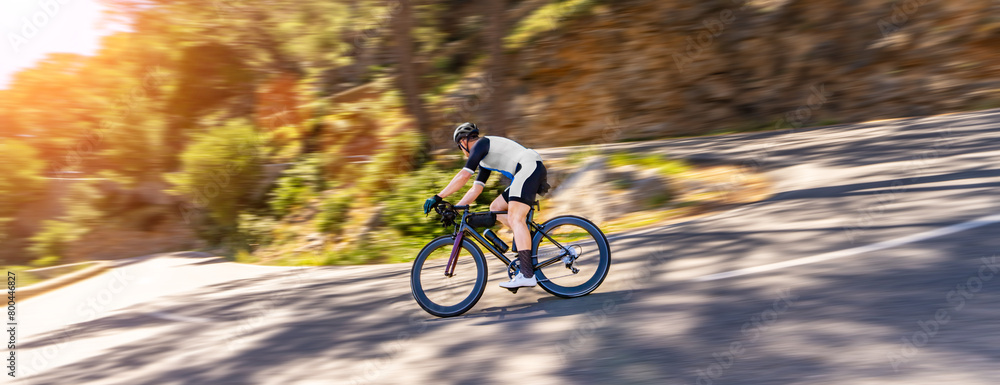 Mature Adult on a racing bike climbing the hill at mediterranean sea landscape coastal mountain road - mallorca mountains