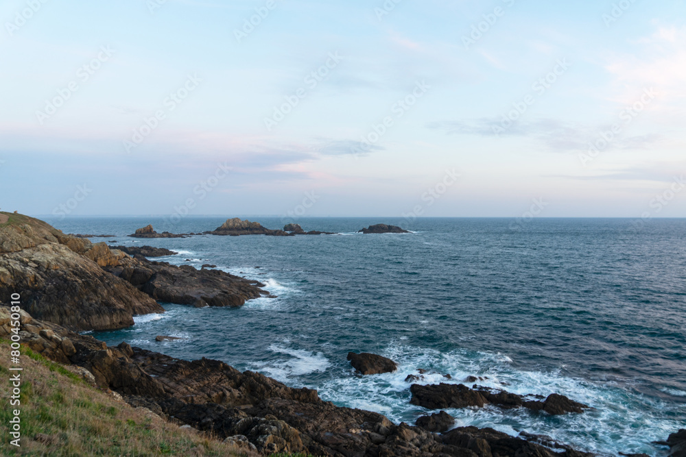 Falaises rocheuses et îlot rocheux façonnent la côte sauvage de la Pointe Saint-Mathieu, où le ressac rencontre la majestueuse mer d'Iroise, un paysage saisissant de la Bretagne.