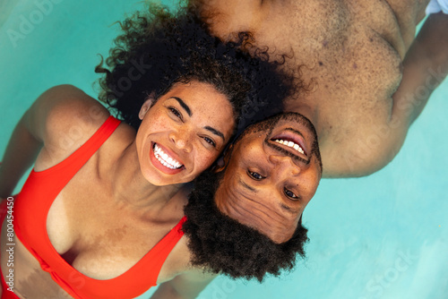 A Happy Couple Floats In Pool With Heads Near Each Other photo
