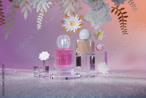 glass perfume bottles on a sparkling background with paper flowers photo