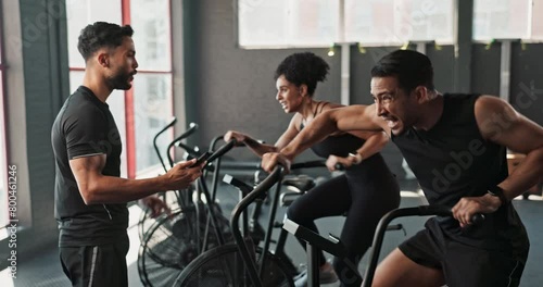 People, instructor and bicycle in gym for exercise, high five in training class for body wellness with workout goal. Coach, cardiovascular fitness or joint mobility, client progress and challenge photo