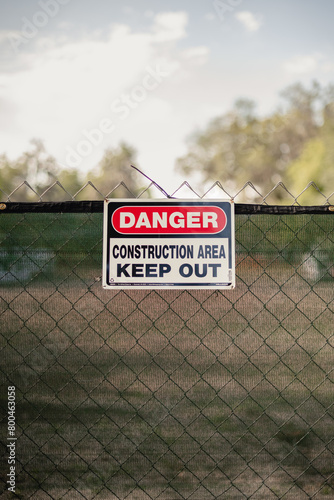 Danger Construction area sign hanging on a chain link fence at a construction site, verticle