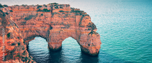 Two arches in the rock. Rock Elephant drinks water. View of Praia da Marinha and Benagil beach in the Algarve region of the Atlantic Ocean, Portugal. Horizontal banner photo