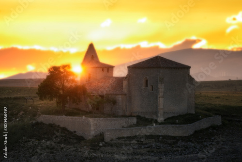 Sunset at the Romanesque church of Valdeajos de la Lora, Burgos, with the sun setting behind the bell tower photo