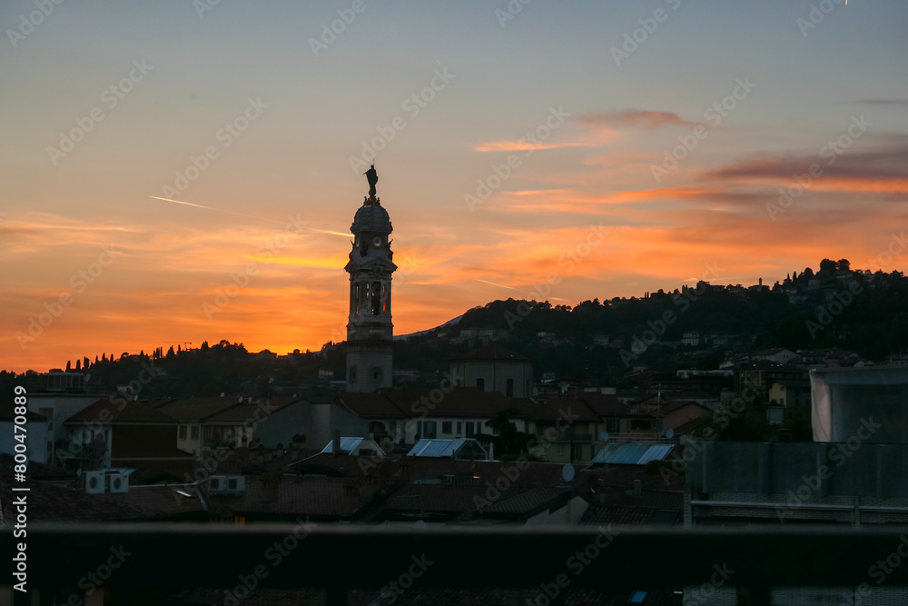 Scenic sunset view of tower of  church Chiesa di Sant Alessandro della Croce the town of Bergamo, Lombardy, Northern Italy, Europe. Romantic atmosphere in historical old town. Silhouette of buildings