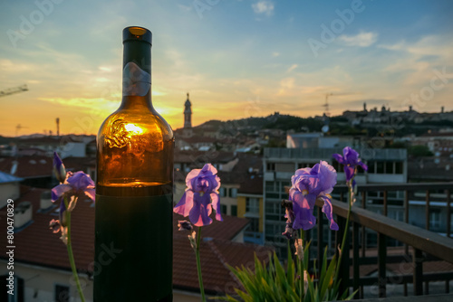 Bottle of wine with scenic sunset view of tower of church Chiesa di Sant Alessandro della Croce the town of Bergamo, Lombardy, Northern Italy, Europe. Silhouette of buildings in historical old town