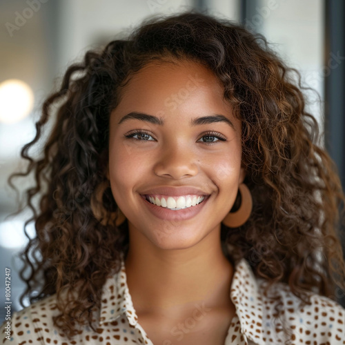 Professional headshot portrait of a gorgeous, clear, dark-skinned woman with perfect teeth and naturally curly hair smiling at the camera