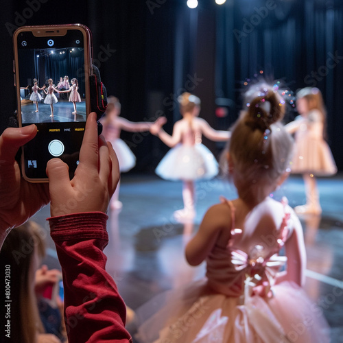 Family Support: A sibling takes a video of her younger sister who is preparing to go on stage and dance for her ballet recital, with sparkly tinsel in her hair and a cute pink silk and tulle tutu gown