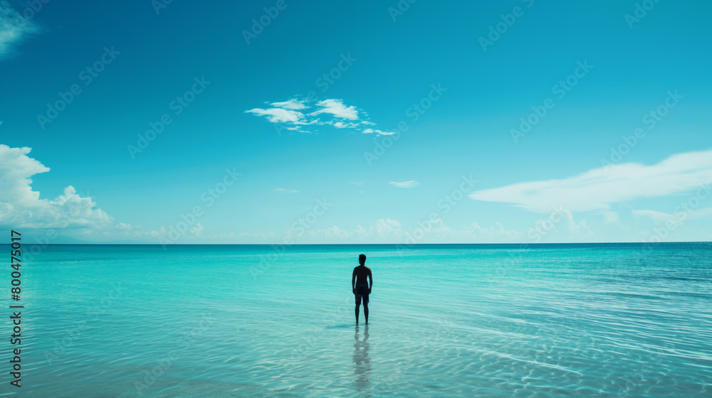 Clear turquoise waters invite a solitary figure wading with a beautiful blue sky overhead and a whisper of clouds Clear turquoise waters invite a solitary figure wading with a beautiful blue sky overhead and a whisper of clouds