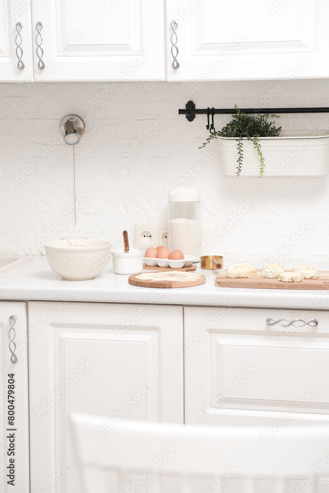 Home kitchen interior.Bowl with dough and spatula, eggs and bowl of sugar, napkin on kitchen table in modern kitchen.