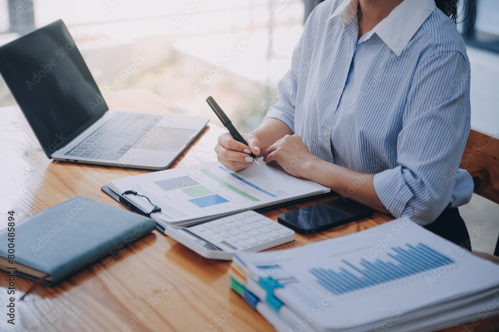 Close up Business woman using calculator and laptop for do math finance on wooden desk, tax, accounting, statistics and analytical research concept Close up Business woman using calculator and laptop for do math finance on wooden desk, tax, accounting, statistics and analytical research concept