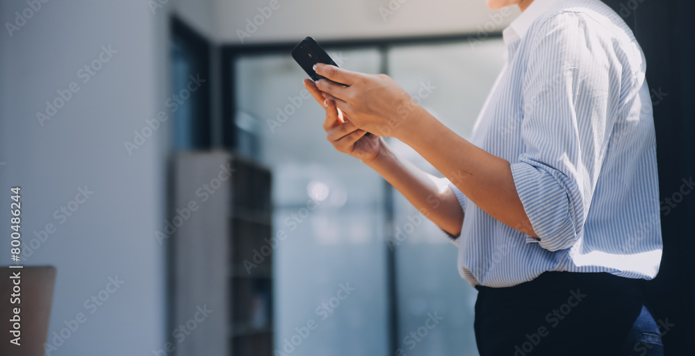 Portrait of a happy Asian businesswoman using mobile phone indoor, Asian businesswoman working in modern office.