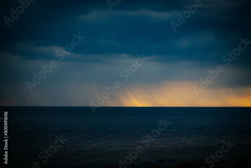 Dark ominous sea with sunset on the horizon in spring. Soft selective focus. Artificially created grain for the picture